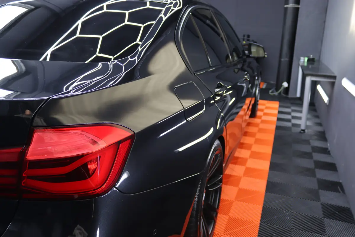 Heck eines schwarzen BMW mit Hexagon-Reflexionen im Lack